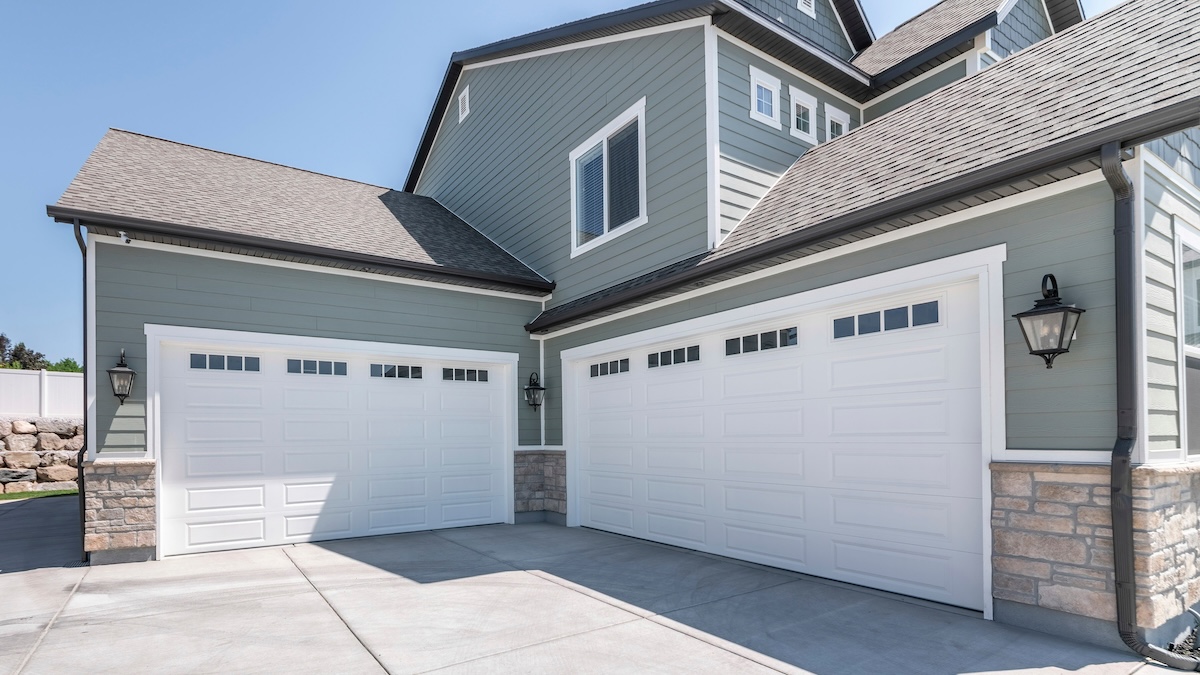 Pano Exterior of a house with concrete driveway and two closed white garage doors with windows