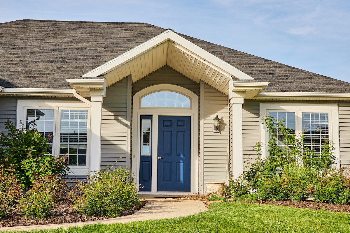 Gray siding house blue front door, arch entryway, slate gray checkered roof landscaping asset