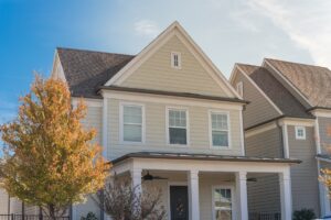 Upscale cottage style homes in suburbs Dallas, Texas with wood siding, covered porch patio with ceiling fans. Colorful autumn leaves and white cladding layer thermal insulation, weather resistance