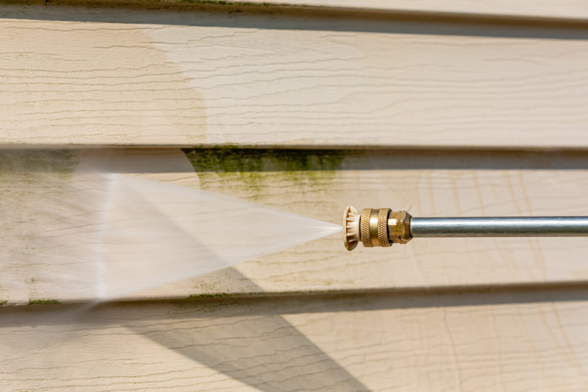 Cleaning algae, mold and mildew from vinyl siding of house with pressure washer. Home repair, maintenance and exterior cleaning concept. how to clean vinyl siding