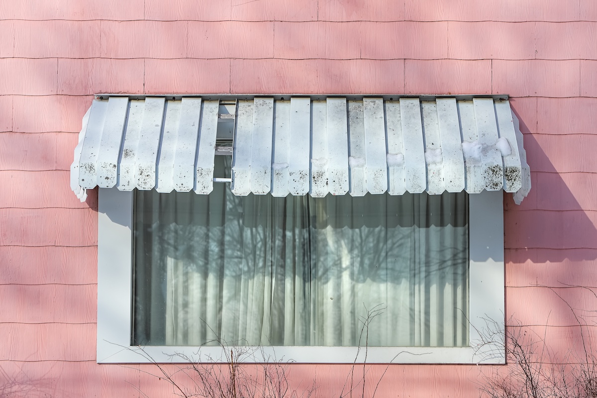 Pink shingle asbestos siding on a house in winter window with awning
