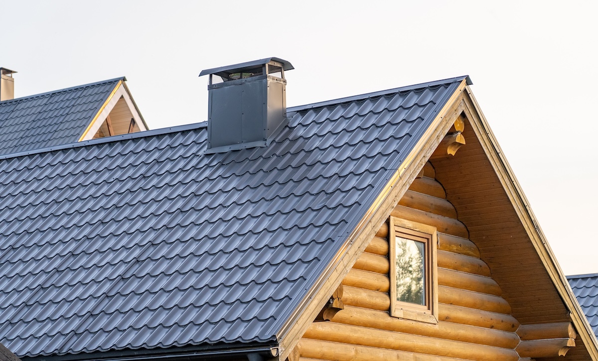 house siding options A log cabin features a sleek metal shingle roof and chimney, showcasing a blend of rustic charm and contemporary design in natural light