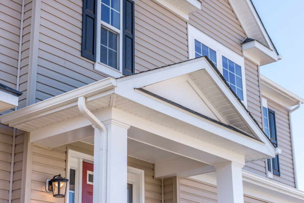 lap siding Portico leading to the entrance of vinyl horizontal lap siding covered building, with a roof structure over a walkway, supported by white rectangular columns on a new single family home in Maryland