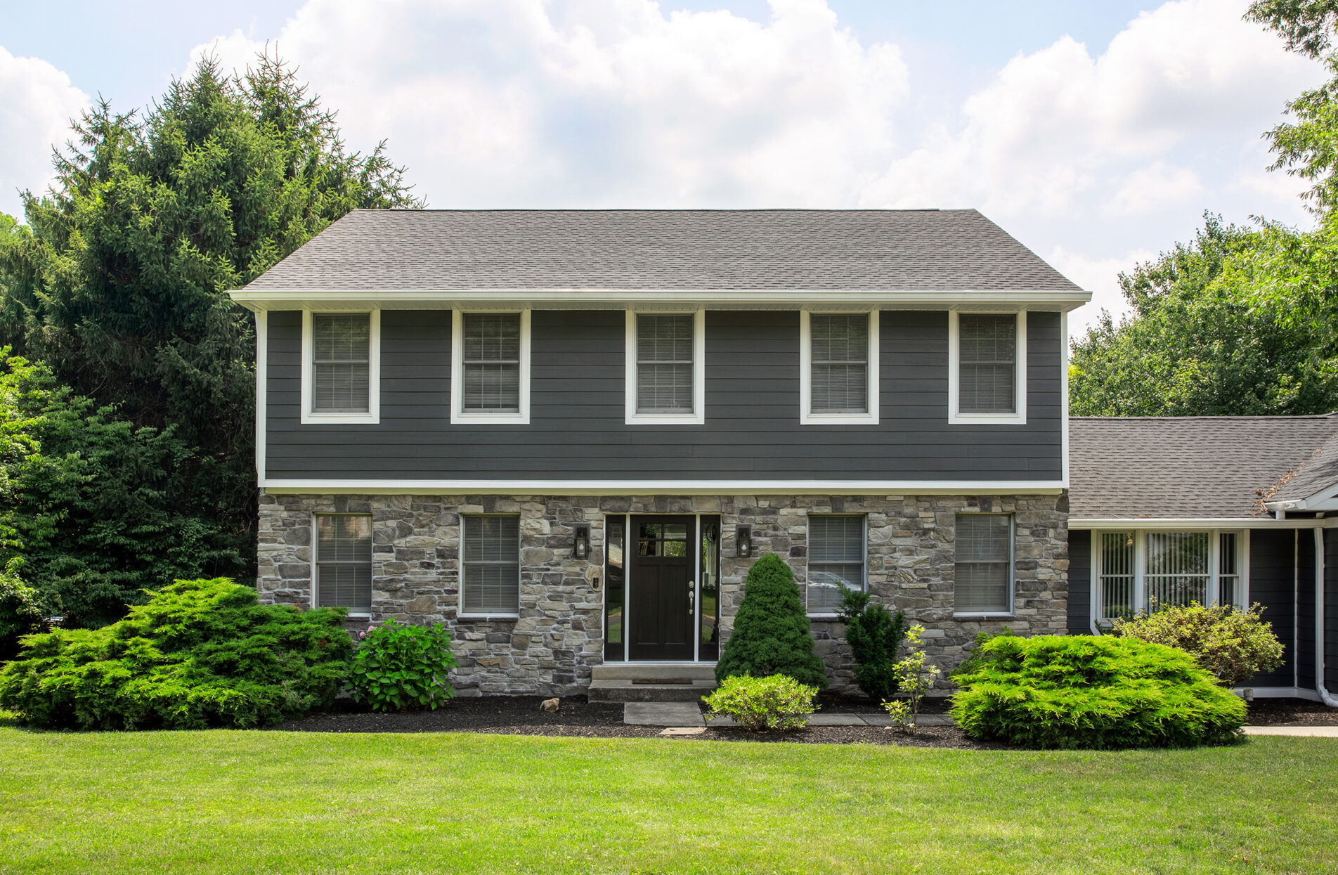 Two-story home with charcoal lap siding and stone